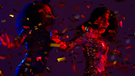 Close-Up-Of-Two-Women-In-Nightclub-Bar-Or-Disco-Dancing-With-Falling-Confetti-And-Sparkling-Lights